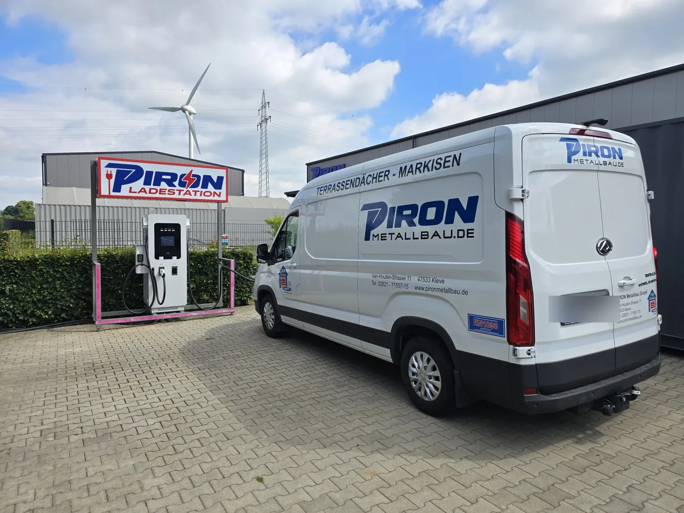 Die PIRON Schnellladesäule auf dem Betriebsgelände in Kleve, daneben ein Firmenwagen