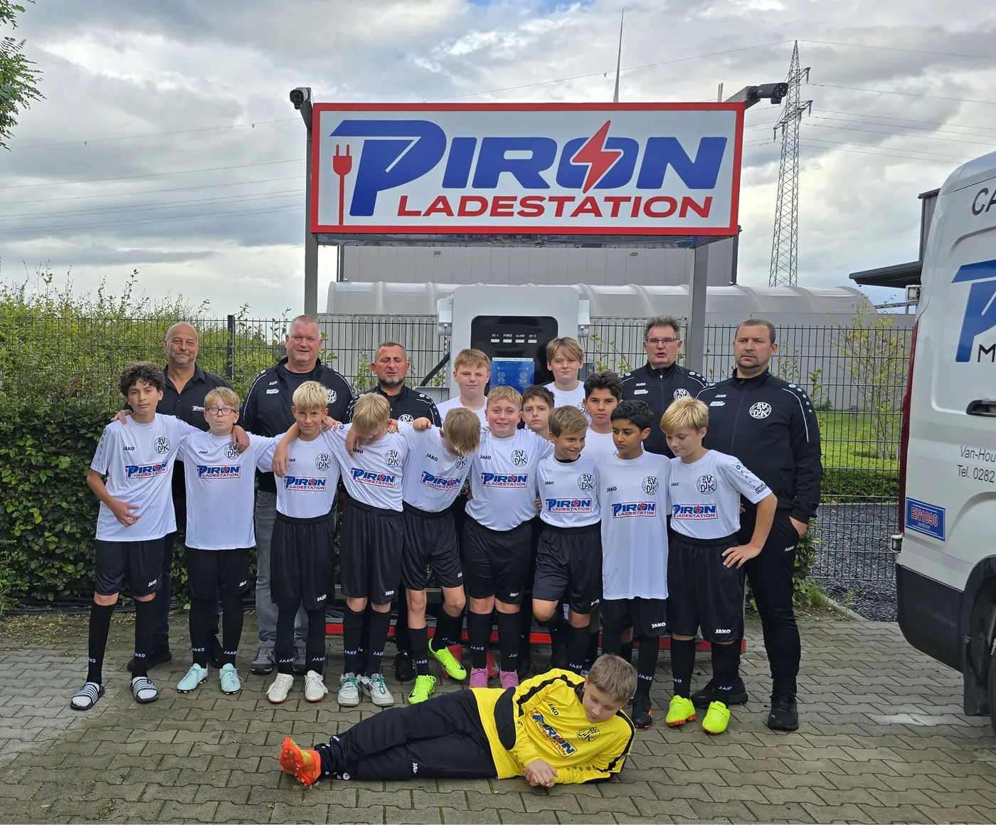 Die D1-Junioren des BV DJK Kellen in den neuen weißen Trikots mit PIRON-Logo, mit ihren Trainern vor der PIRON Ladestation in Kleve